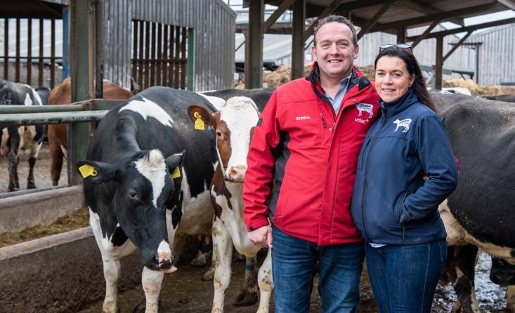 a man and woman posing with cows